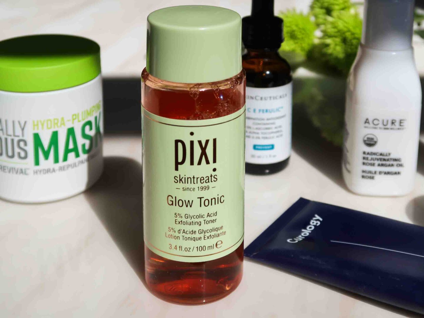 Close-up of skincare products, especially Pixi Glow Tonic